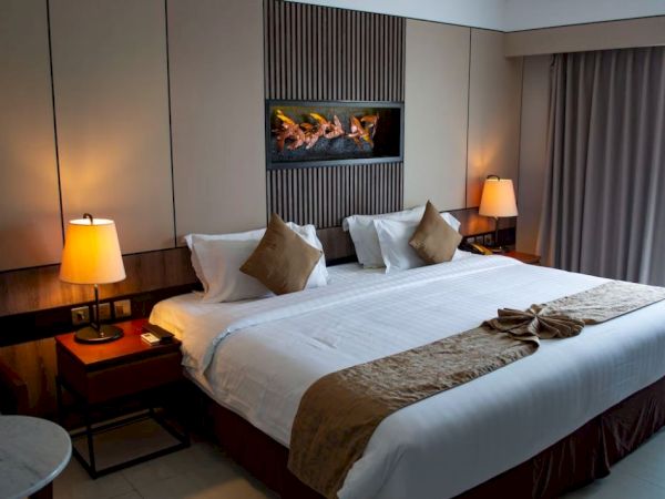 A cozy hotel room with a large bed, decorative pillows, two lamps, and curtains, exuding a warm and inviting ambiance.
