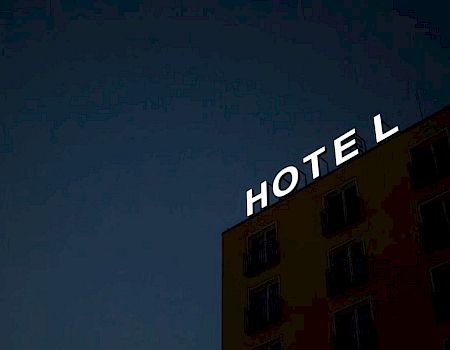 A building with "HOTEL" sign in white letters under a dim, dark sky is visible.