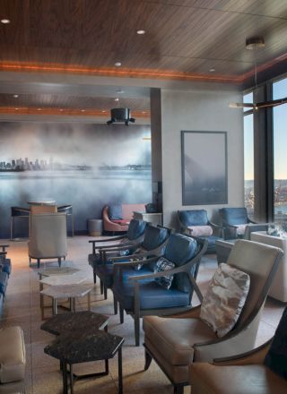 A stylish lounge with modern seating, large windows offering a scenic view, and wall decor depicting a city skyline.