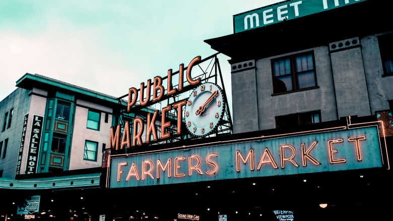 The image shows a neon sign for a "Public Market" and "Farmers Market" on a building, likely capturing a well-known market entrance.